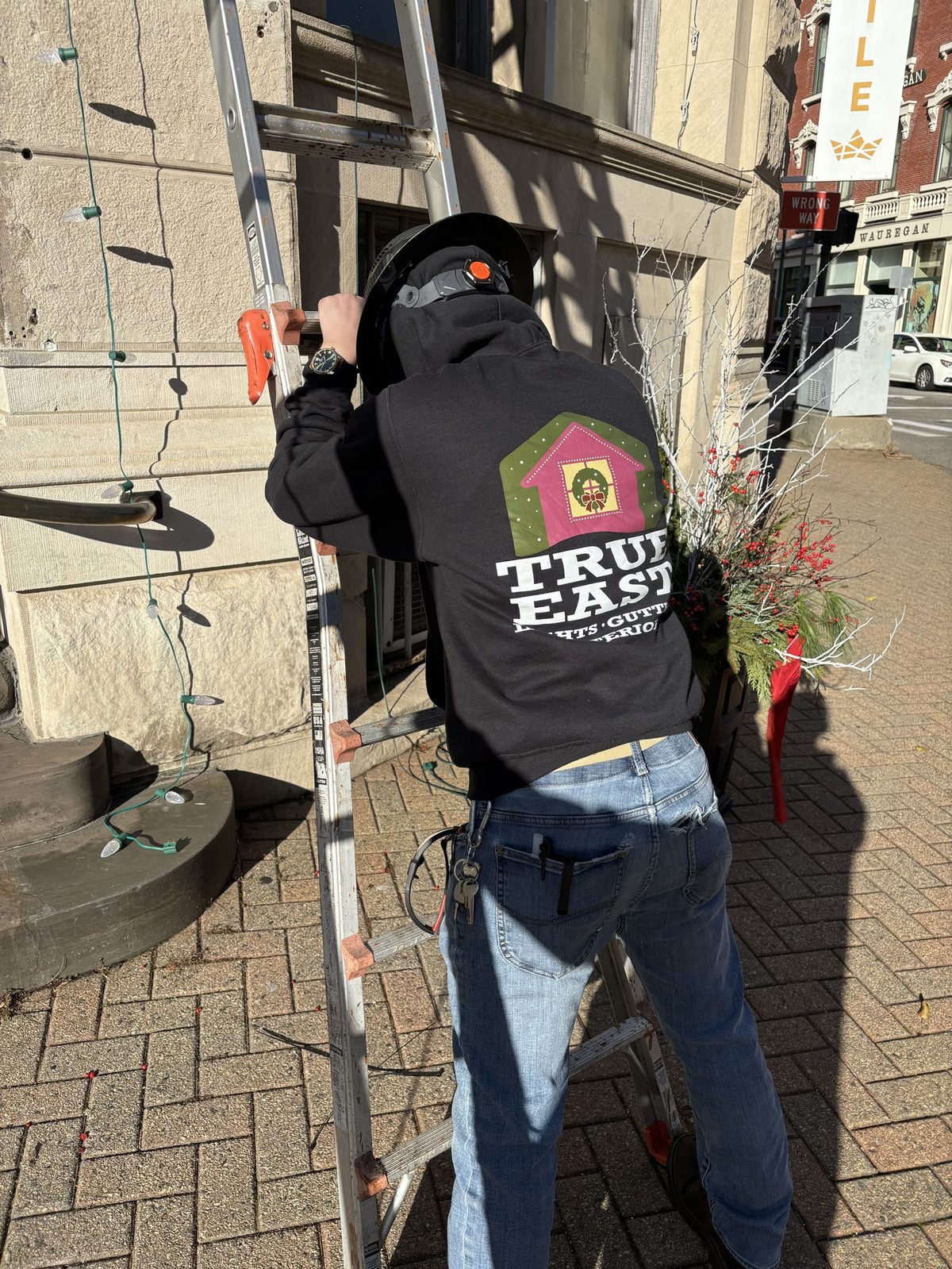 True East crew member on a ladder during a downtown install