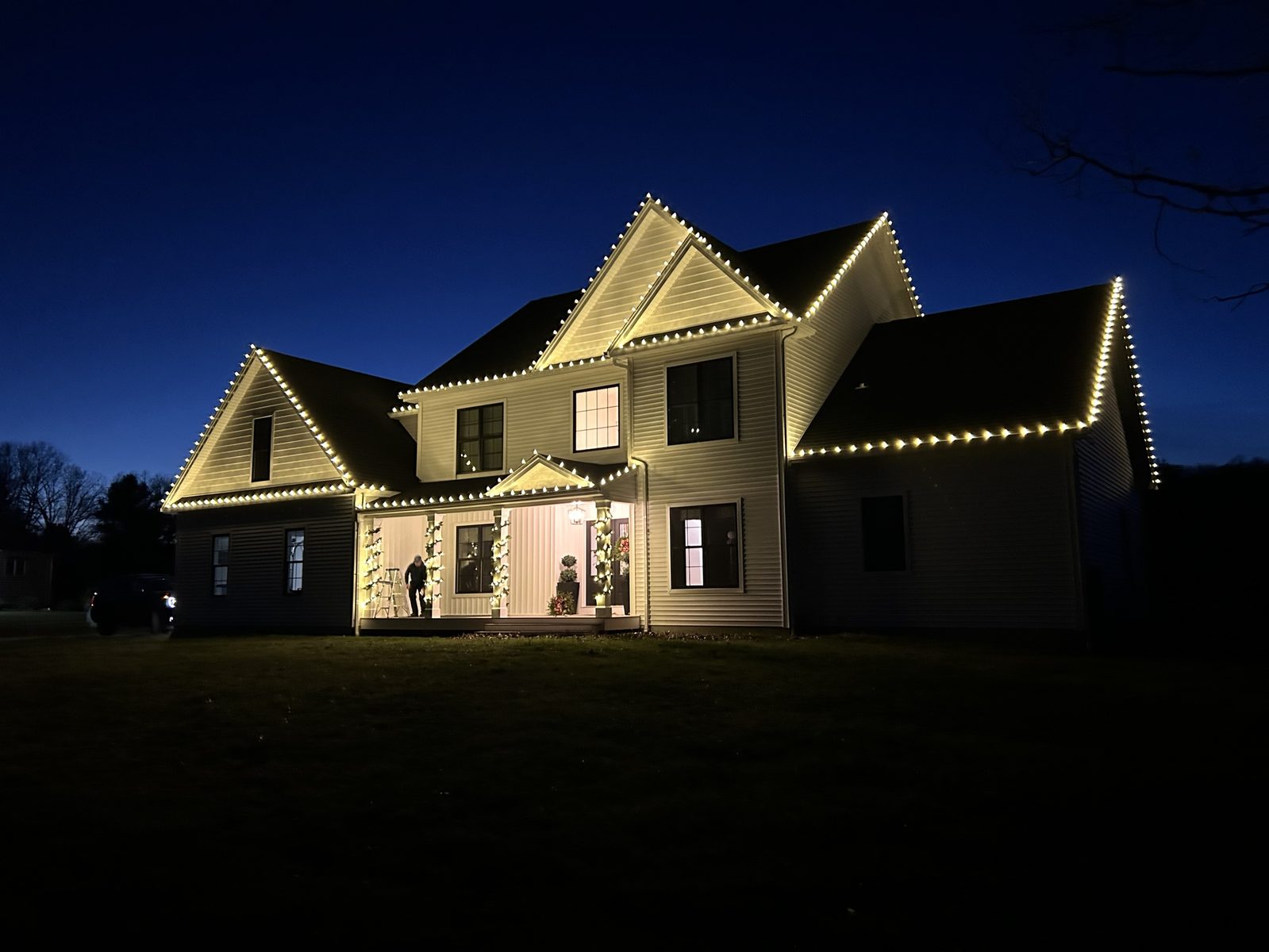 Large Colonial home at dusk with every roofline and gable outlined in warm white C9 lights