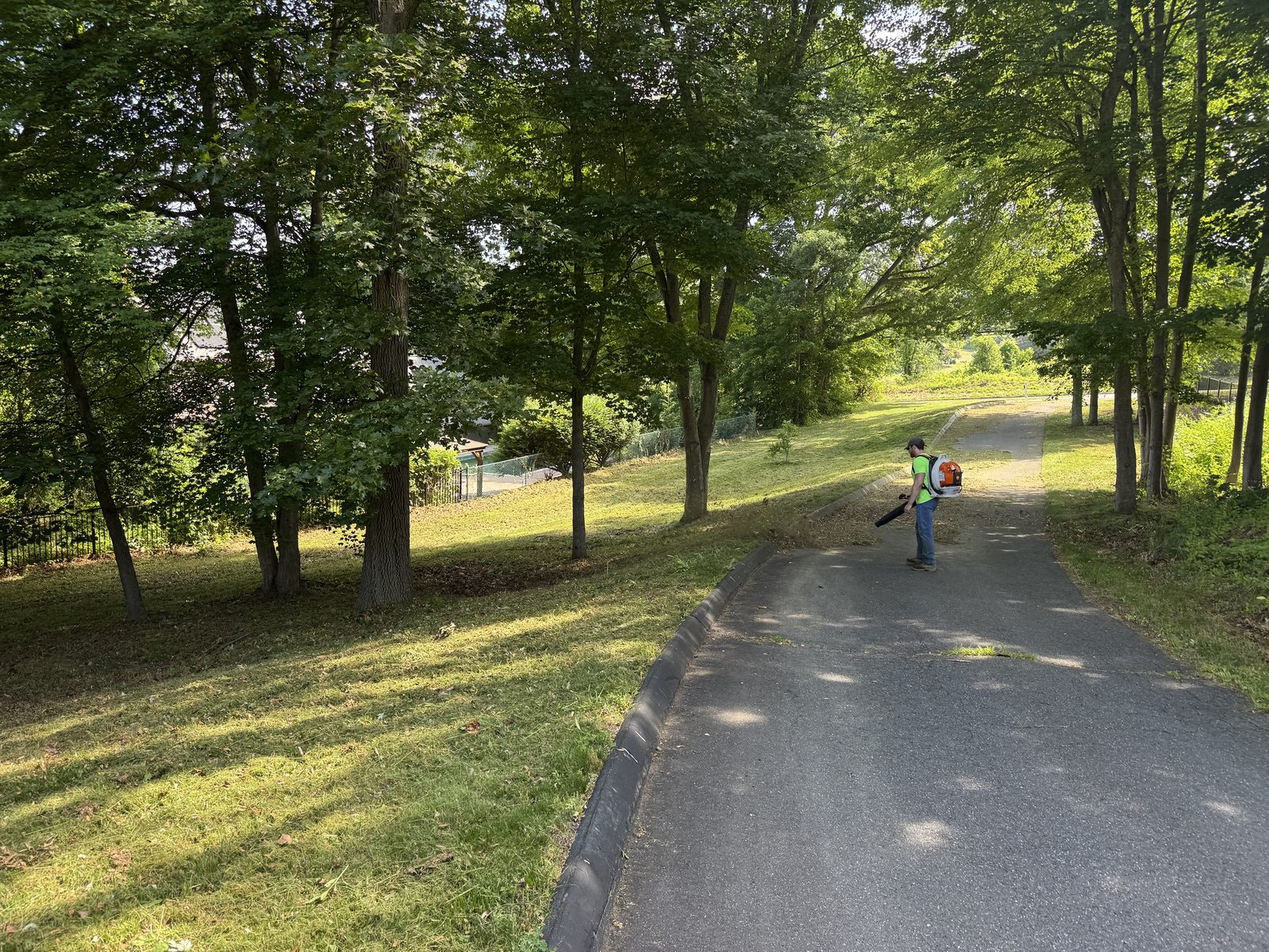 Crew member blowing clippings off a paved path