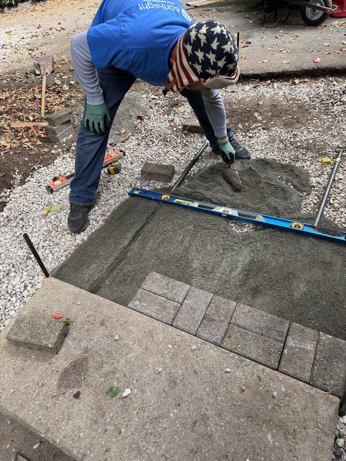 Crew screeding sand and laying pavers for a new walkway