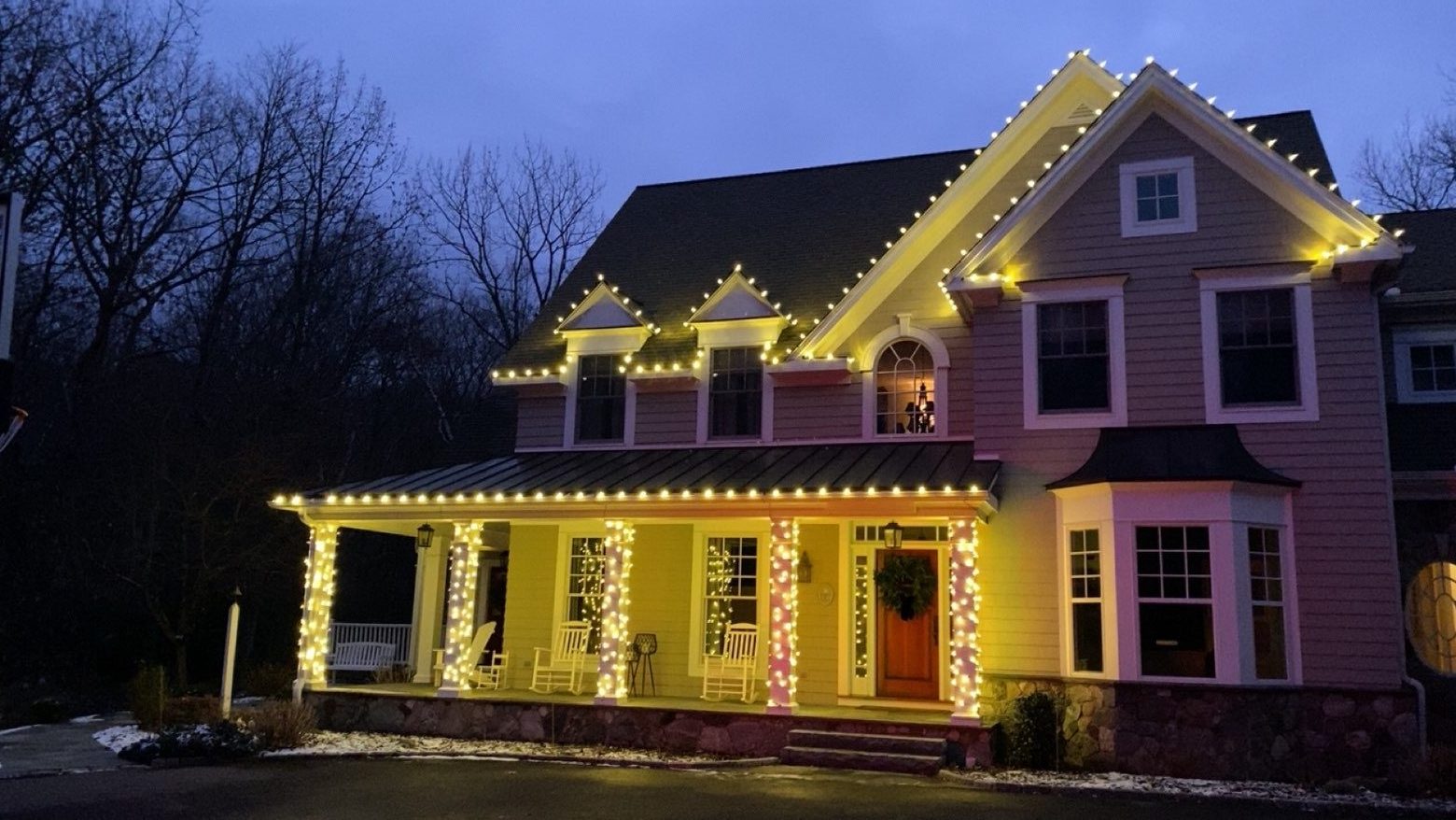Home with lit rooflines, dormers and porch railings